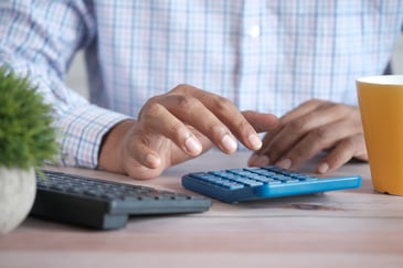 A businessman's accountant using a calculator to total the businessman's corporation tax reliefs for his business